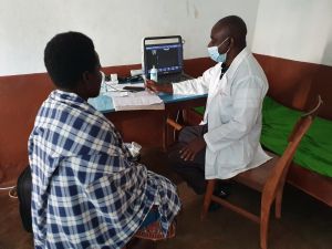 Der Radiologe Dr. Maurus Ndomba bespricht mit einem Patienten die Ergebnisse der Ultraschalluntersuchung.