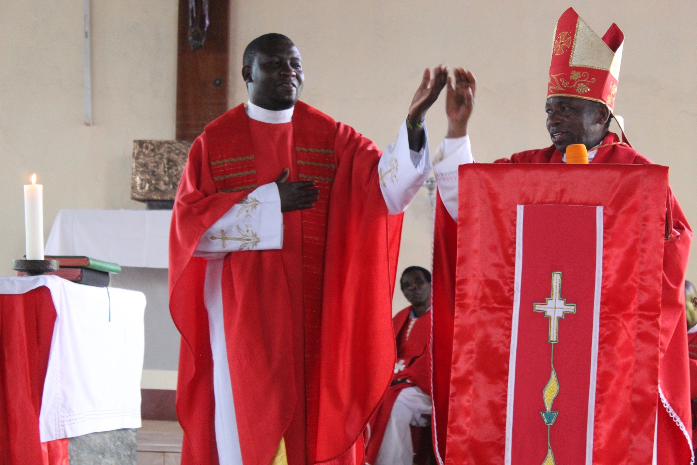 Bischof John Ndimbo führt Pater Dennis Aura CMM als Pfarrer ein